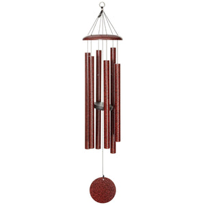 The Corinthian Bells® 44-inch Windchime is a red metallic wind chime with multiple cylindrical tubes hanging from a circular top, featuring a red disc at the bottom and adding a touch of flair.