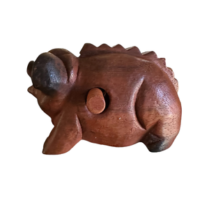 A handmade Wooden Musical Pig Percussion Instrument with a round protruding detail on its side, carved with simple features and a slightly glossy finish, displayed against a white background.