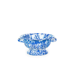 Splatter Enamelware Small Berry Colander in blue and white features distinctive speckled enamel, two convenient side handles, and a small pedestal base. Its durable porcelain finish makes it perfect for both rinsing berries and serving them, showcased beautifully against a white background.