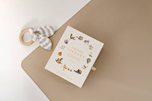 Our Little Library, a board book with first words, featuring a collection of vocabulary on a beige surface with a ring.