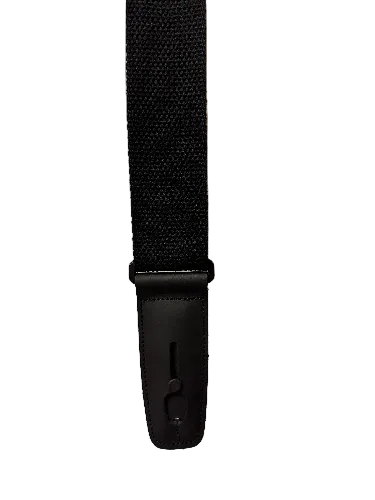 The Lock-It Black Cotton Strap is a vertical black guitar strap made with a textured woven cotton band and a leather end tab that features a keyhole-shaped cutout for a strap button.