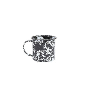 The Splatter Enamelware 12 oz Mug, featuring a black and white speckled design and convenient handle, is showcased against a white background—ideal for serving your guests with style.