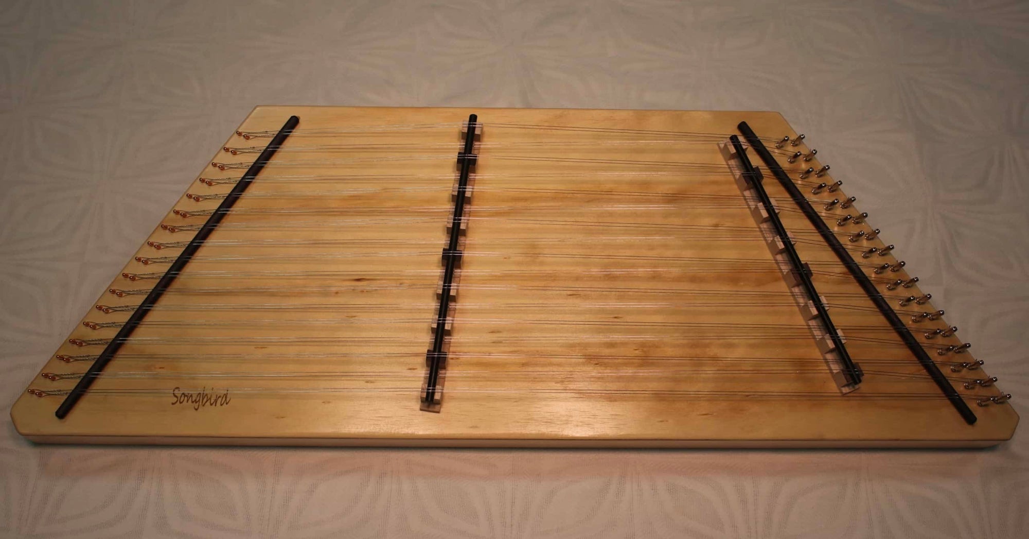 A Two String 9/8 Fledgling Songbird Hammered Dulcimer with several strings on it that requires tuning.