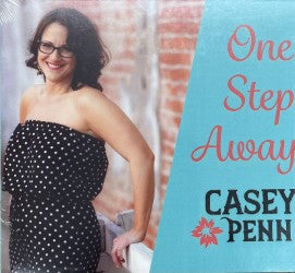 A woman in a polka dot dress stands by a brick wall, accompanied by the text "One Step Away by Casey Penn.