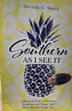 The book cover displays a pineapple, a symbol of Southern hospitality, alongside the title "Southern As I See It" by Cindy Smith, with an "Autographed Copy" sticker on it. The narrative charms readers with its focus on Southern traditions and etiquette.