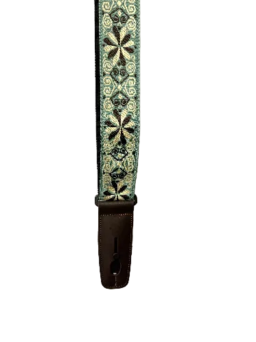 A section of the Lock-It Green Flowers Jacquard Strap, a guitar strap with a leather end piece, featuring green, beige, and black geometric flower patterns.