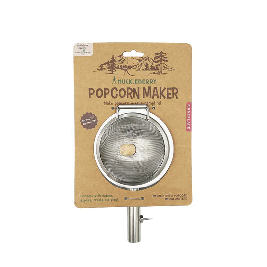 The Huckleberry Popcorn Maker is a packaged popcorn popper featuring a metal mesh basket and a wooden handle, ideal for campfire cooking. Designed specifically for making popcorn over an open flame, it includes clear instructions and brand labeling on the packaging.