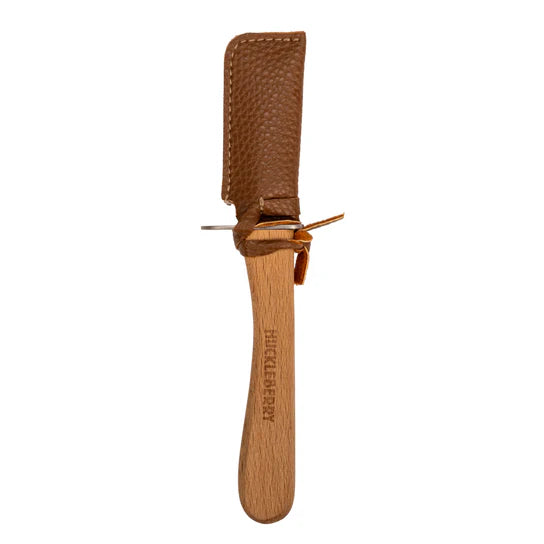 A wooden carving knife with a textured leather cover labeled "Huckleberry," reminiscent of learning practical life skills.