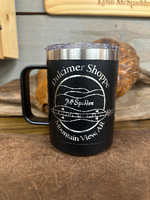McSpadden Dulcimer Shoppe Insulated Mug w/Handle featuring “Dulcimer Shoppe, McSpadden, Mountain View, AR” and a laser-engraved dulcimer graphic on the side, shown on a brown surface.