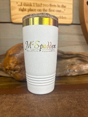 The McSpadden Dulcimer Shoppe Insulated Coffee Mug features a white design, a silver lid, and the “McSpadden Mountain Dulcimers” logo. Shown on a wooden surface with a blurred wood background, this stylish mug is perfect for keeping your favorite beverages at the ideal temperature.