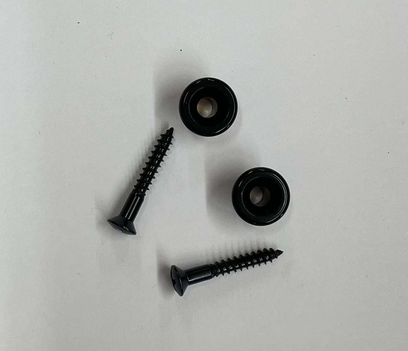 Two Black Strap Buttons (Pair) on a white surface.