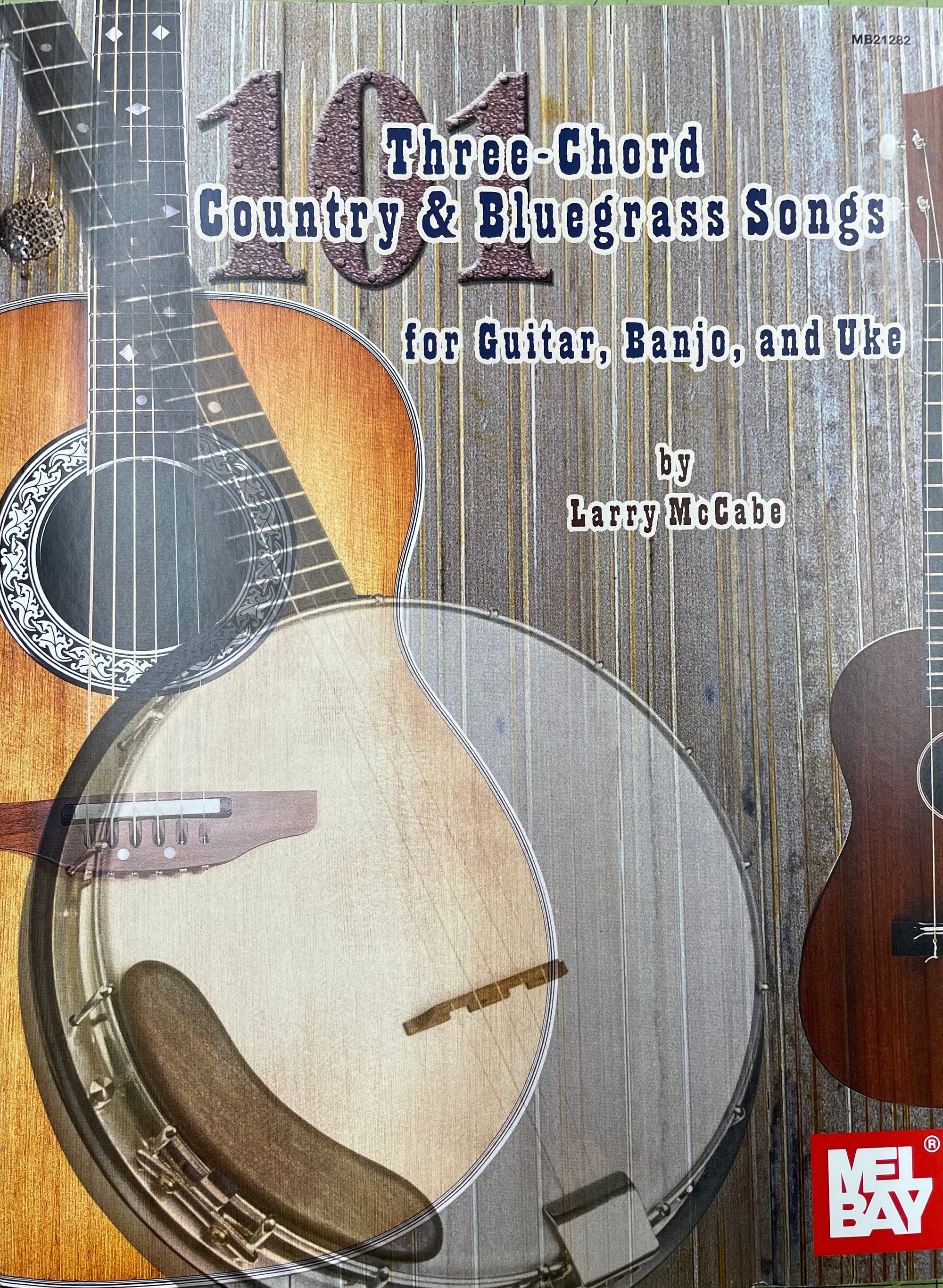 A music book titled "101 Three-Chord Country & Bluegrass Songs for Guitar, Banjo, and Uke" by Larry McCabe, displayed with a guitar and banjo, includes chords with diagrams.