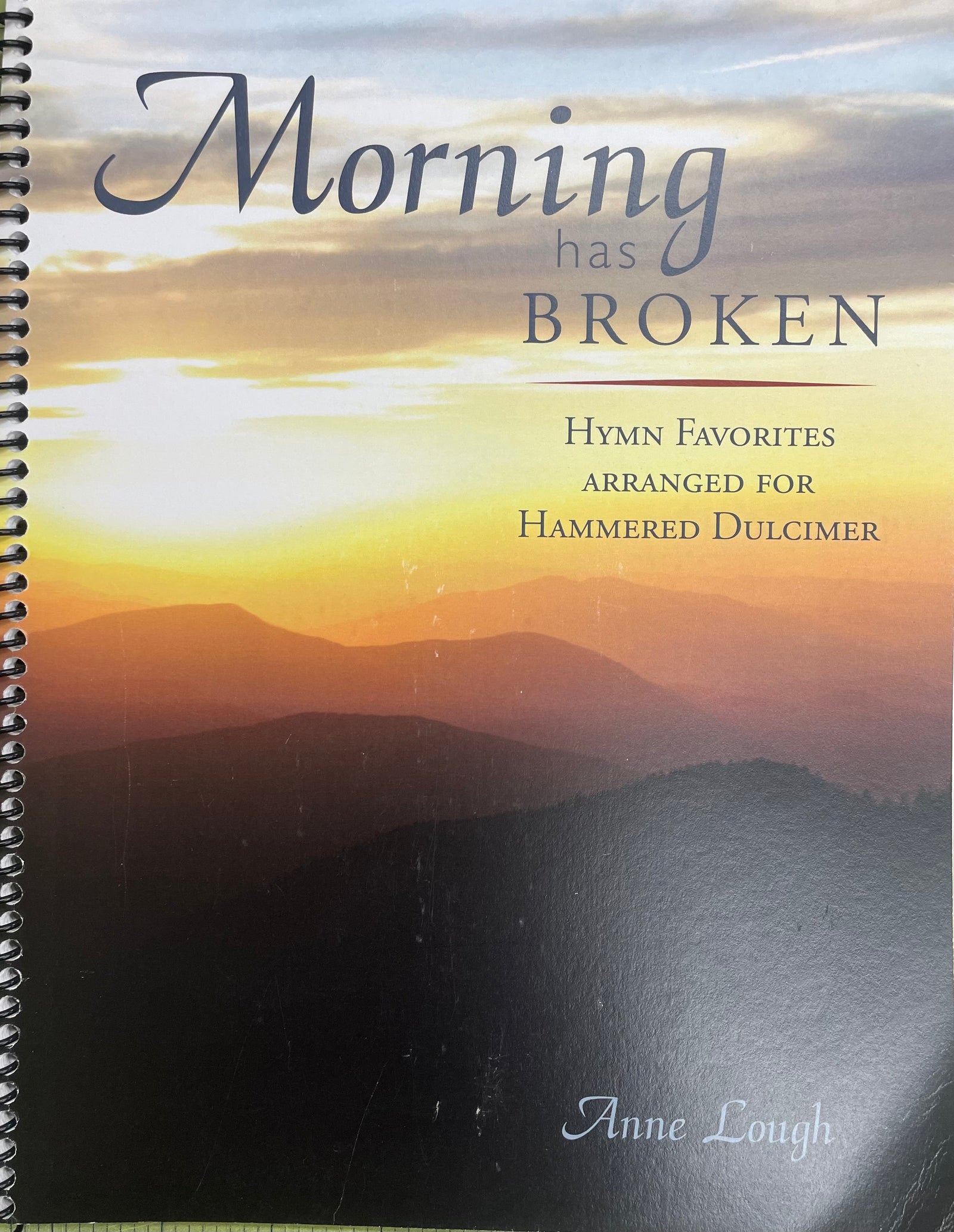 Spiral-bound book titled "Morning Has Broken by Anne Lough" featuring a sunrise over mountains on the cover.