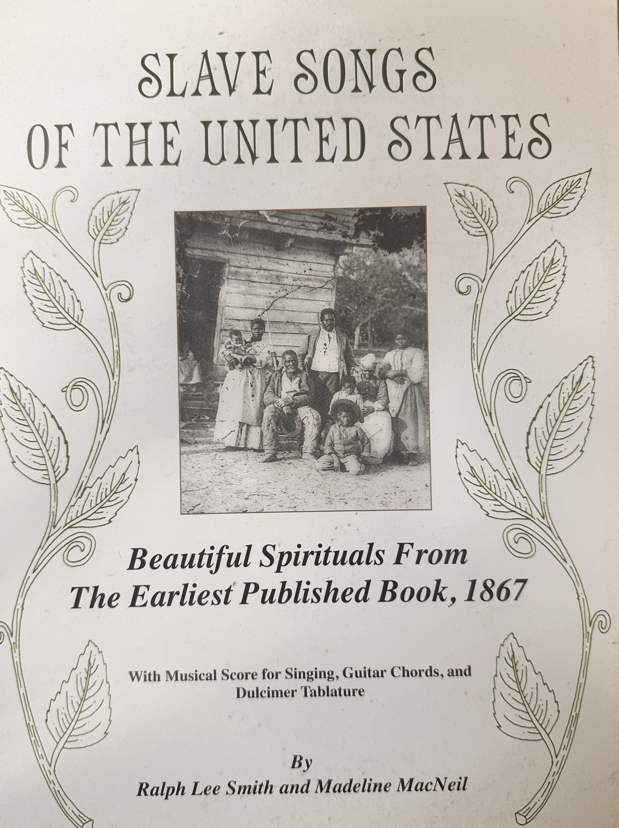 The cover of "Slave Songs of the United States by Ralph Lee Smith and Madeline MacNeil" showcases a photograph of people dressed in 19th-century attire with a log cabin in the background. The text emphasizes spirituals and music from 1867, encapsulating the essence and soul of that era through its musical score.