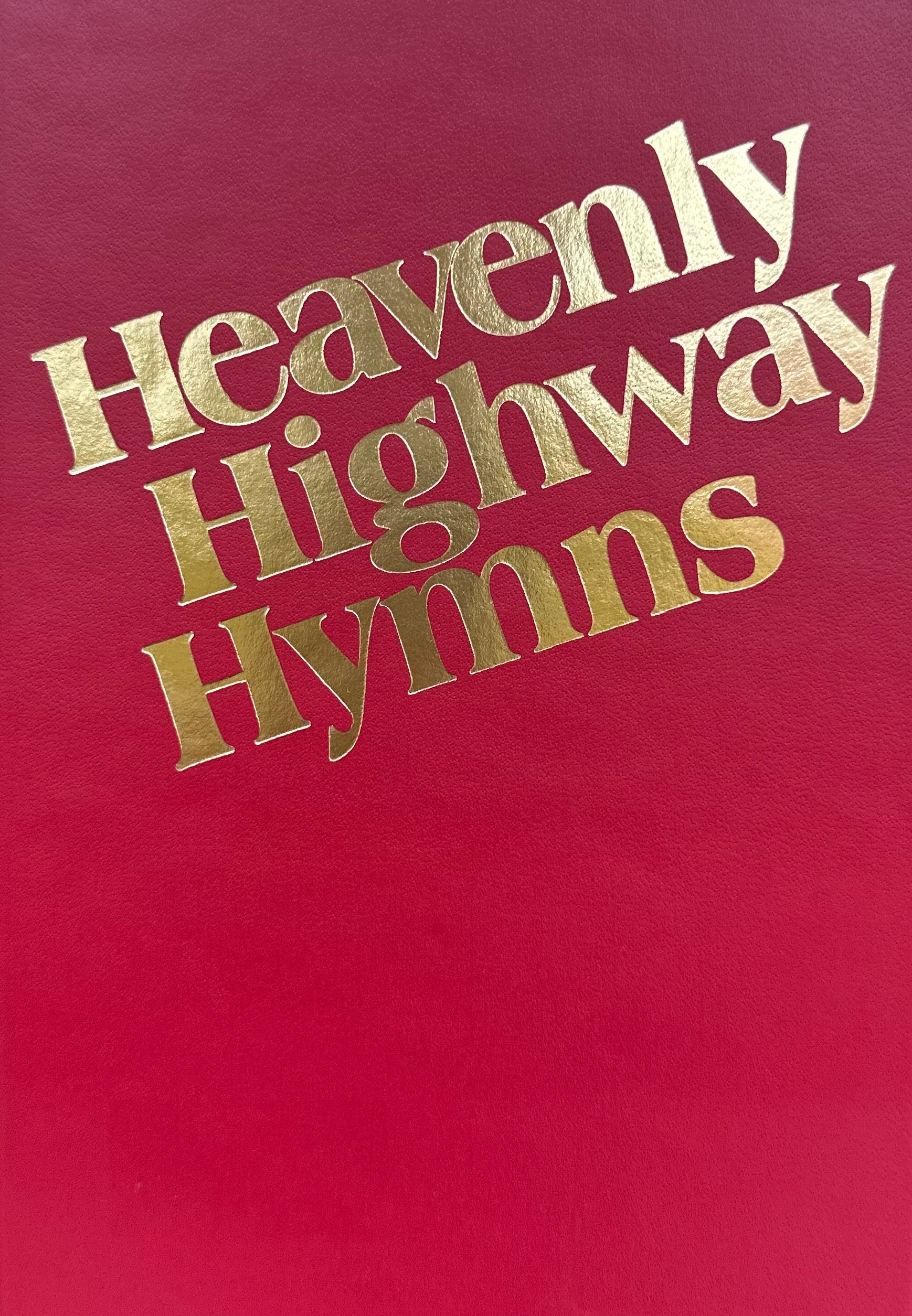 A red book cover featuring gold text with the title "Heavenly Highway Hymns RED.