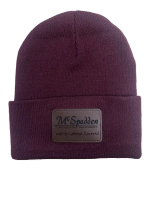 The Beanie Knit Cap with McSpadden Logo Patch is a maroon knit beanie featuring a folded brim and a rectangular patch that reads "McSpadden" and "We've Gotcha Covered.