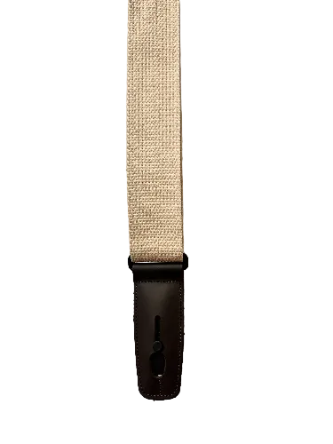 The Lock-It Natural Cotton Strap is a beige woven guitar strap featuring a dark brown leather end piece and black adjuster hardware, displayed against a white background.