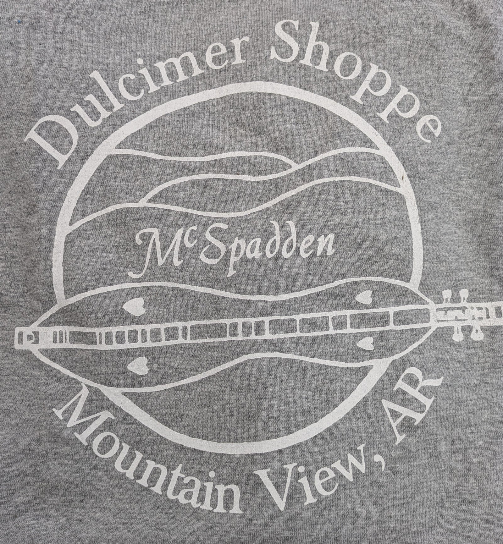 The Long Sleeve T-shirt - Dulcimer Shoppe Logo is gray with a white dulcimer graphic and “Dulcimer Shoppe, McSpadden, Mountain View, AR” in a circle. Available in sizes Small to 3XL.