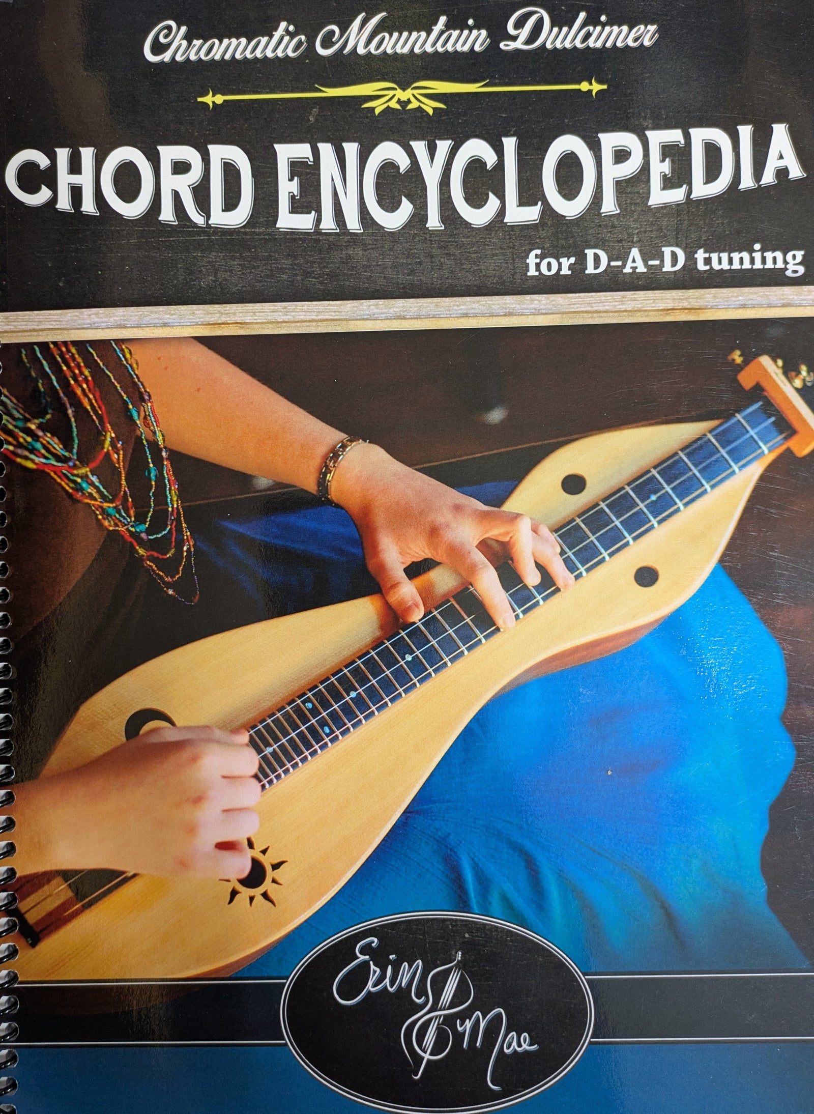 Cover of the "Chromatic Mountain Dulcimer Chord Encyclopedia by Mae," showing a person playing a chromatic mountain dulcimer, chord charts, and the author's name, Erin Mae, at the bottom.