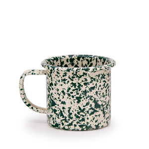 The Splatter Enamelware 12 oz Mug features a cream base with a green splatter pattern, large handle, and flared rim—perfect for adding charm to any colorful serveware collection. Shown on a plain white background.