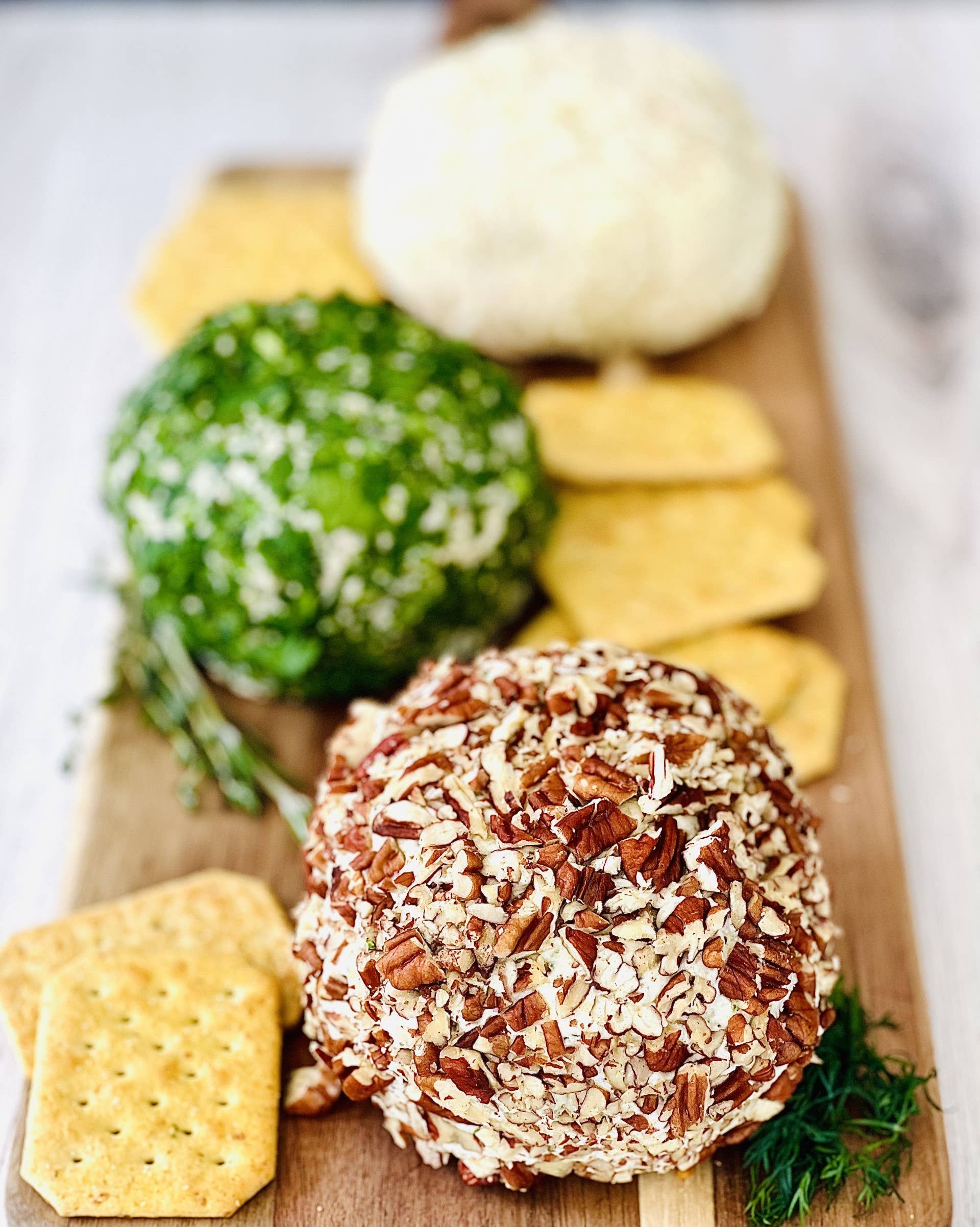 A festive holiday gift featuring the Mariachi Mexican Appetizer Cheeseball surrounded by an assortment of crackers and nuts, elegantly displayed on a rustic wooden board.