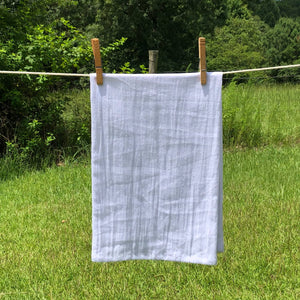 A Sweet Tea and Jesus tea towel hanging on a clothes line in a field.