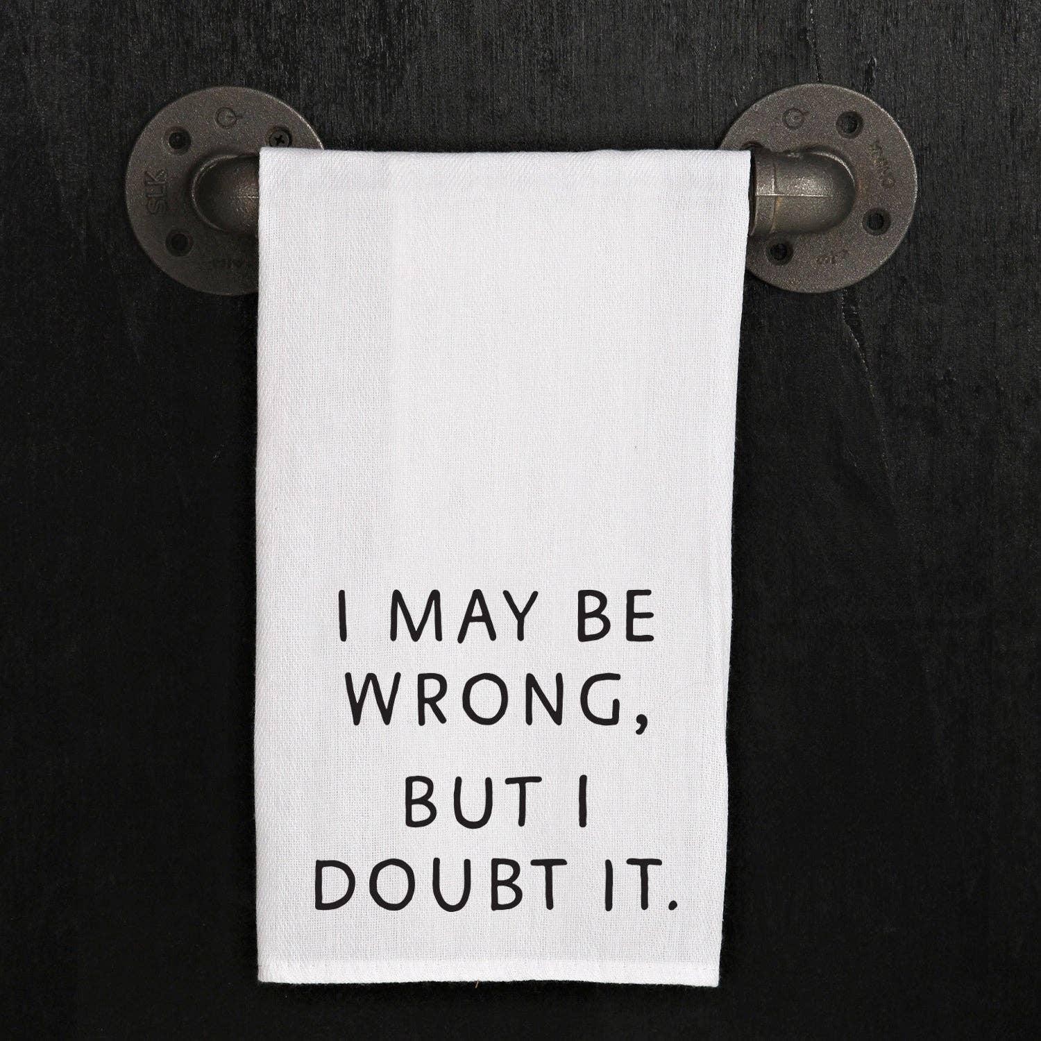 A white towel featuring black text that reads "I may be wrong, but I doubt it" hangs on a black wall-mounted metallic pipe. This versatile item, the "I May Be Wrong but I Doubt It" kitchen towel, serves as a witty and practical addition to any space, making it an excellent handmade hostess gift.
