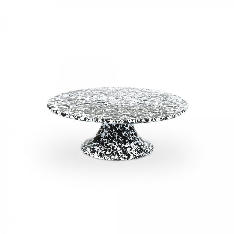 The Splatter Enamelware Cake Stand features a black and white speckled design, a wide round top, and a sturdy base—perfect for entertaining or serving in style, shown here on a plain white background.