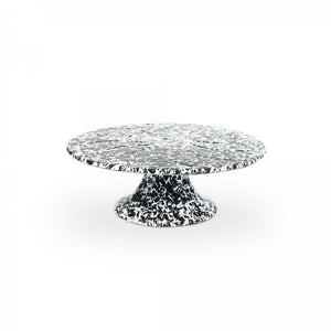 The Splatter Enamelware Cake Stand features a black and white speckled design, a wide round top, and a sturdy base—perfect for entertaining or serving in style, shown here on a plain white background.