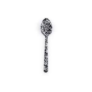 A Splatter Enamelware Large Slotted Spoon, featuring a black and white speckled pattern reminiscent of classic enamelware, is centered on a plain white background.