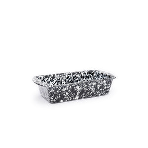 The Splatter Enamelware Loaf Pan is a black and white speckled rectangular baking dish with two small side handles, shown against a plain white background. This oven-safe pan features a durable porcelain finish for lasting style and function.