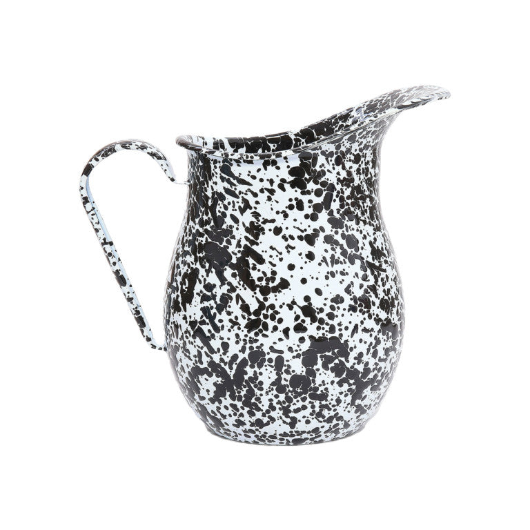 The Splatter Enamelware Large Pitcher features a distinctive black splatter pattern on white enamel, a curved handle, and a wide spout. Set against a plain white background, this 3 qt pitcher blends classic charm with practical style.