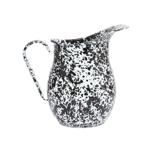The Splatter Enamelware Large Pitcher features a distinctive black splatter pattern on white enamel, a curved handle, and a wide spout. Set against a plain white background, this 3 qt pitcher blends classic charm with practical style.