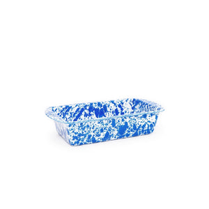 The Splatter Enamelware Loaf Pan, displayed on a white background, features a blue and white marbled pattern. This oven-safe piece offers a smooth porcelain finish for easy cleaning and timeless style.