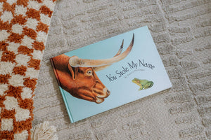 A "You Stole My Name (Picture Book for Kids)" with a cow and a frog on a blanket, featuring delightful illustrations.