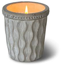 A lit Parisian Courtyard Chic Vase Swan Creek Candle glows inside its textured, gray, patterned holder against a white background.
