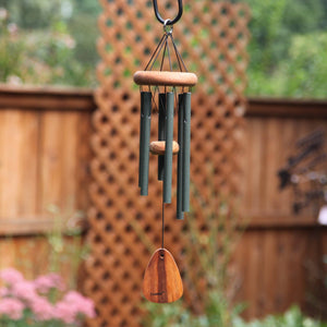 A Festival® 18-inch Windchime hanging from a fence in a garden, serving as an accent piece.