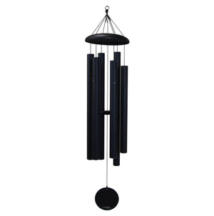 The Corinthian Bells® 60-inch Windchime, featuring multiple black cylindrical chimes and a round striker that produce the harmonious tones of a major 7th chord, is suspended from a hook by strings.