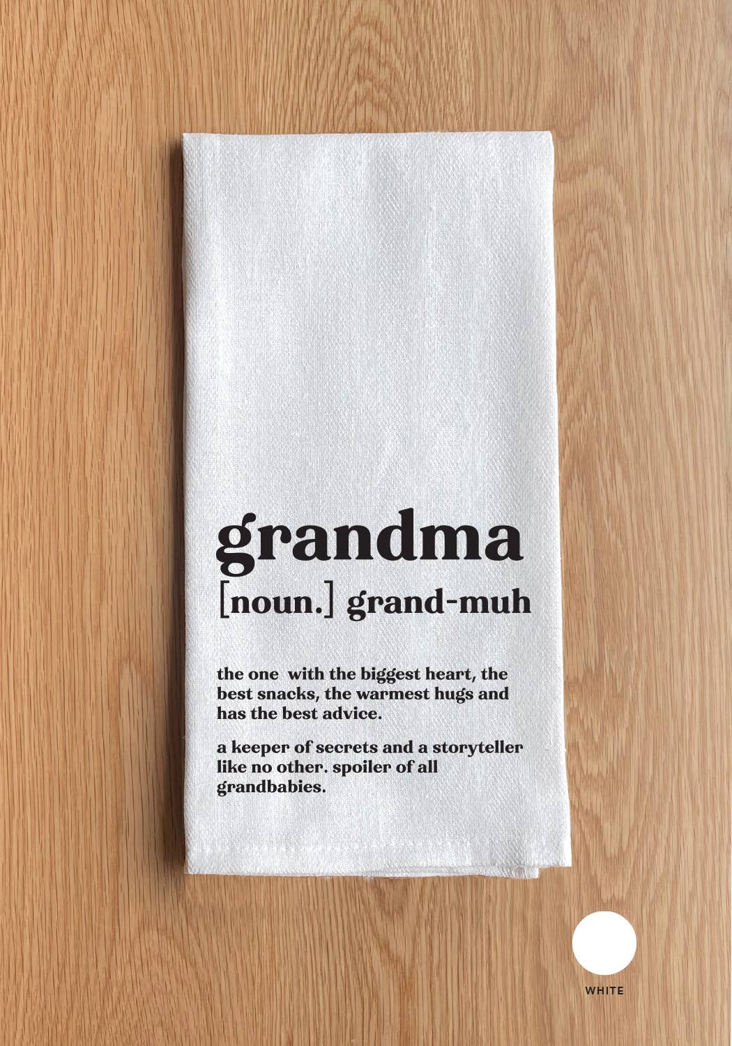 A Grandma definition White Kitchen Towel on a wooden surface with the text: "grandma [noun.] grand-muh. the one with the biggest heart, the best snacks, the warmest hugs, and has the best advice. A keeper of secrets and a storyteller like no other. Spoiler of all grandbabies.