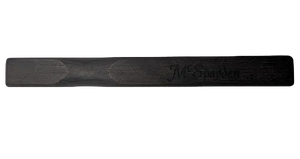 A flat, dark wooden McSpadden Noter with rounded ends and an engraved name.