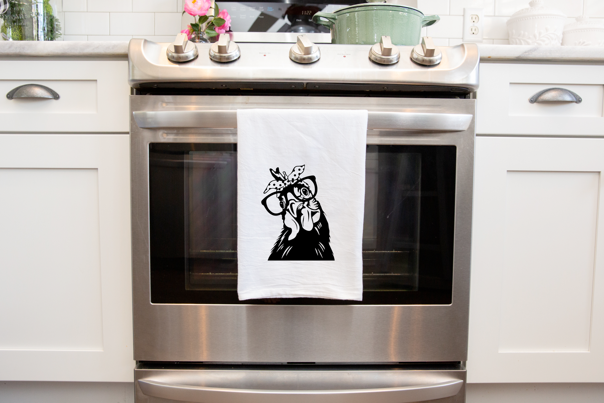 A Funny Chicken Tea Towel made from heat transfer vinyl hangs on the handle of a stainless steel oven.