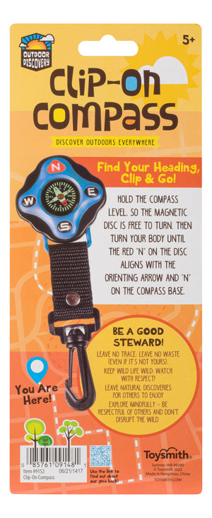 Package of an Outdoor Discovery Backyard Exploration Clip-On Compass by toysmith, designed for outdoor discovery, featuring a compass in a blister pack, labeled for ages 5 and up, with instructions and environmental icons.