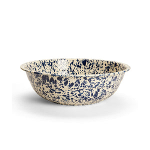 Introducing the Splatter Enamelware Medium Basin: a round bowl crafted from enamelware, featuring a cream base accented with a blue splatter pattern and finished with a porcelain-like sheen. It is pictured against a plain white background.