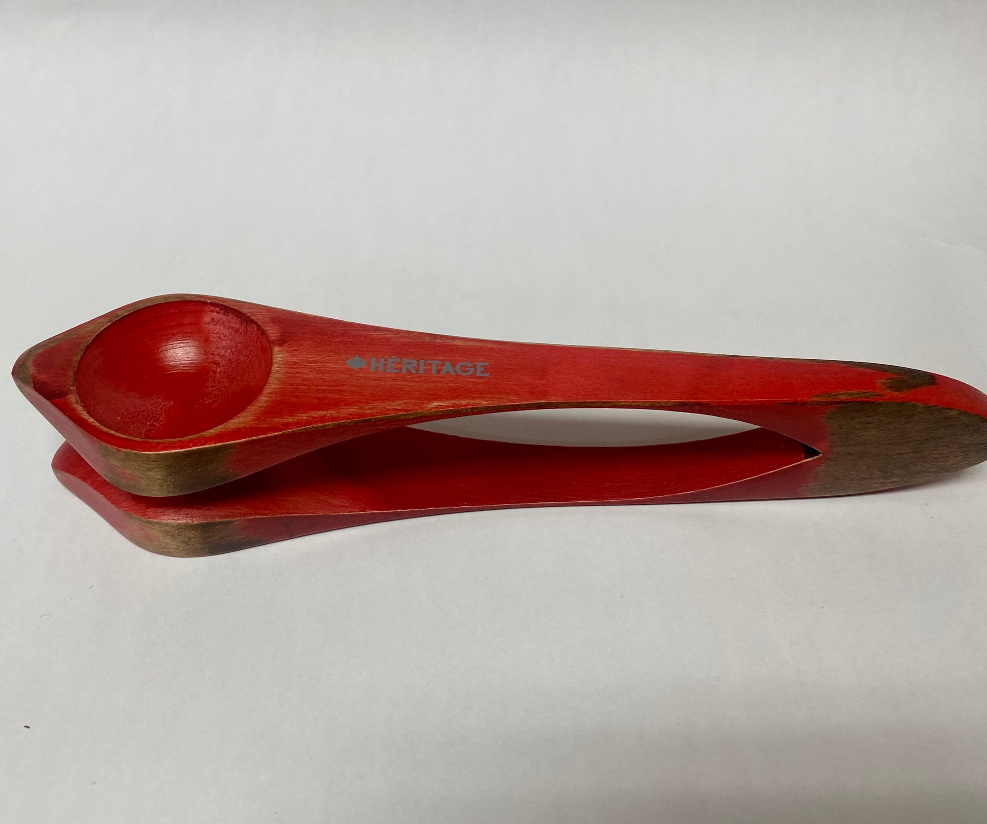 A handmade red Heritage Musical Spoons Medium with a wooden handle.