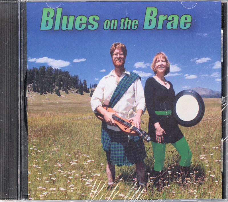 CD cover for "Blues on the Brae" by Taranai featuring a man in a kilt with a guitar and a woman with a drum, set in a field adorned with flowers and mountains in the backdrop.
