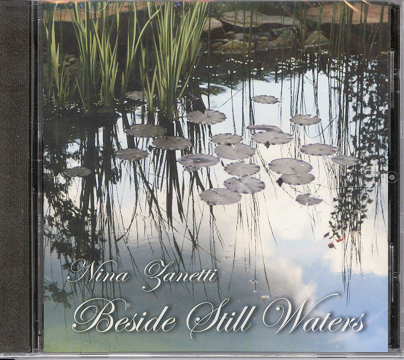 CD cover depicting a tranquil pond adorned with lily pads, reflecting the sky and surrounding flora. The text reads: "Beside Still Waters by Nina Zanetti," highlighting the peace and harmony embodied in Nina Zanetti's new CD.