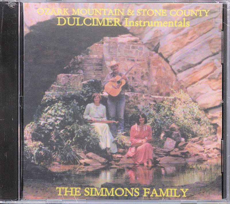 Album cover for "Ozark Mountain and Stone County" by Dancing Doll (Simmons Family), featuring two women and a man with a guitar beside a stone arch and pond, reflecting the essence of traditional tunes played on the mountain dulcimer.