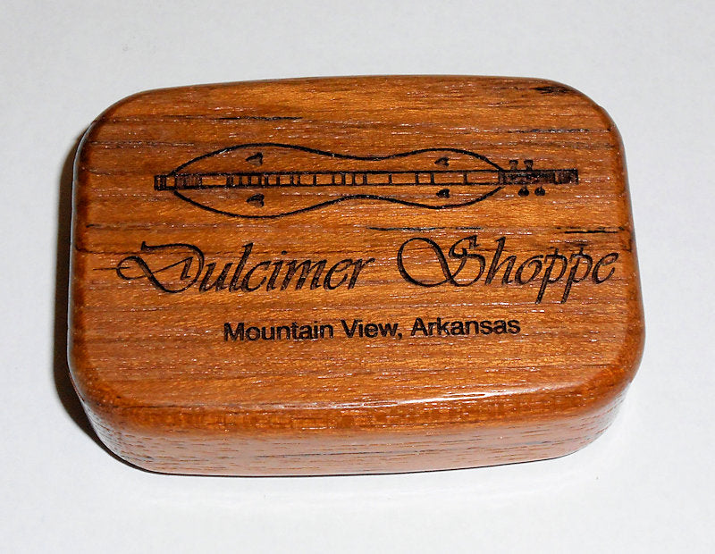 A Dulcimer Shoppe Secret Box Large containing store picks and medicine, adorned with a wooden guitar and surrounded by the words "Mountain View Alabama.