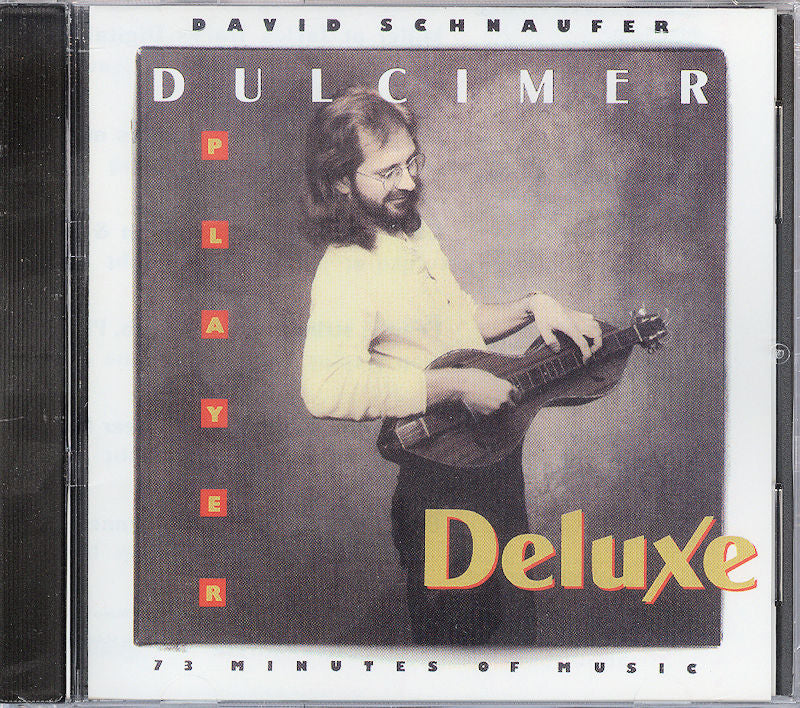 The CD cover of "Dulcimer Player Deluxe," performed by David Schnaufer, depicts a long-haired man with glasses playing the mountain dulcimer. This compilation of 26 traditional songs beautifully captures the essence and charm of this unique instrument.