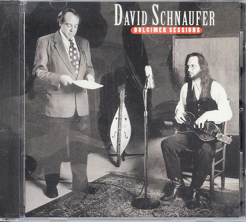 The CD cover of "Dulcimer Sessions by David Schnaufer" showcases two men: one is standing and holding papers, while the other is seated playing a dulcimer, with recording equipment visible in the background.